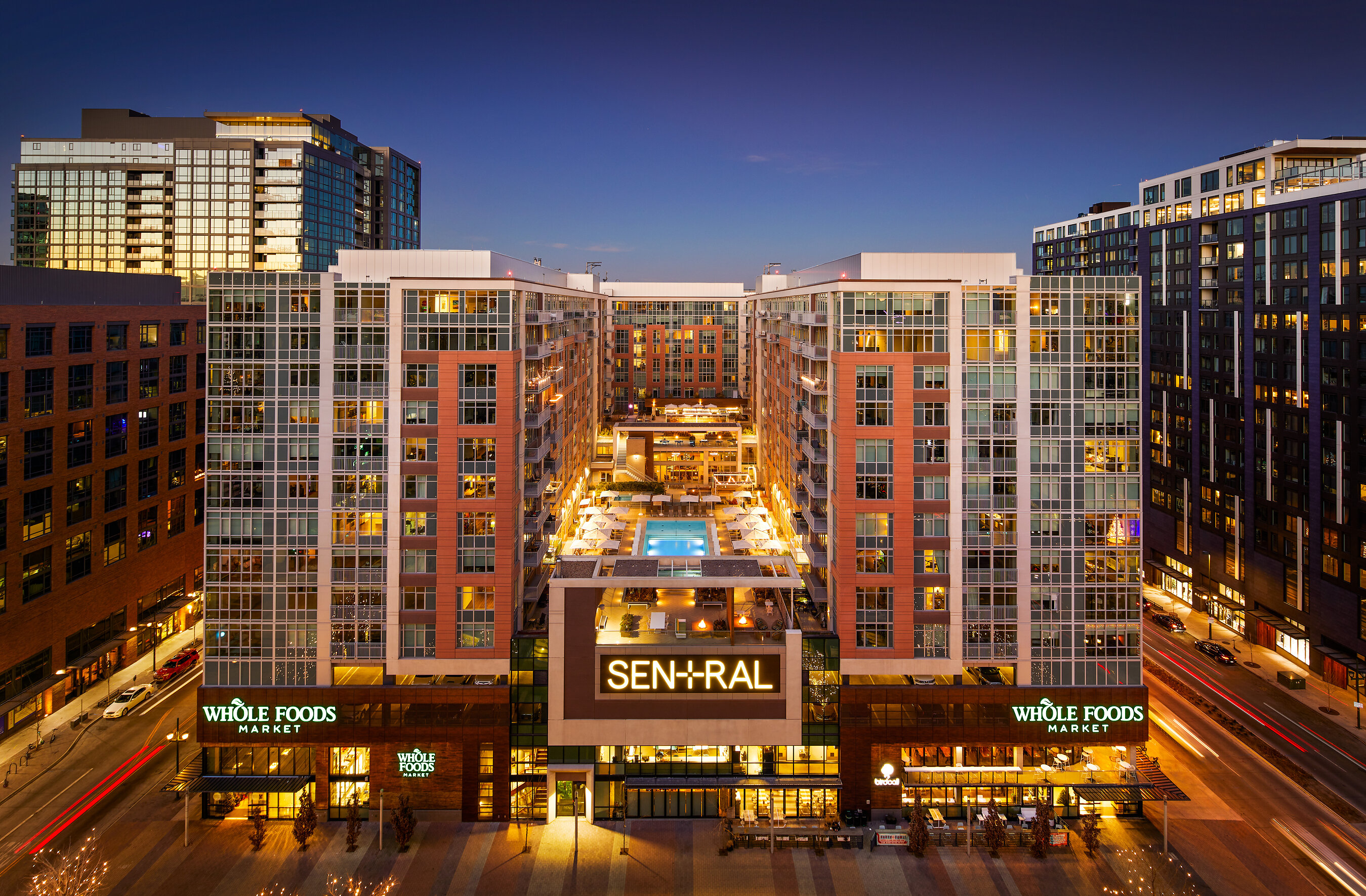 Sentral Union Station in Denver at dusk, with a courtyard pool and Whole Foods below