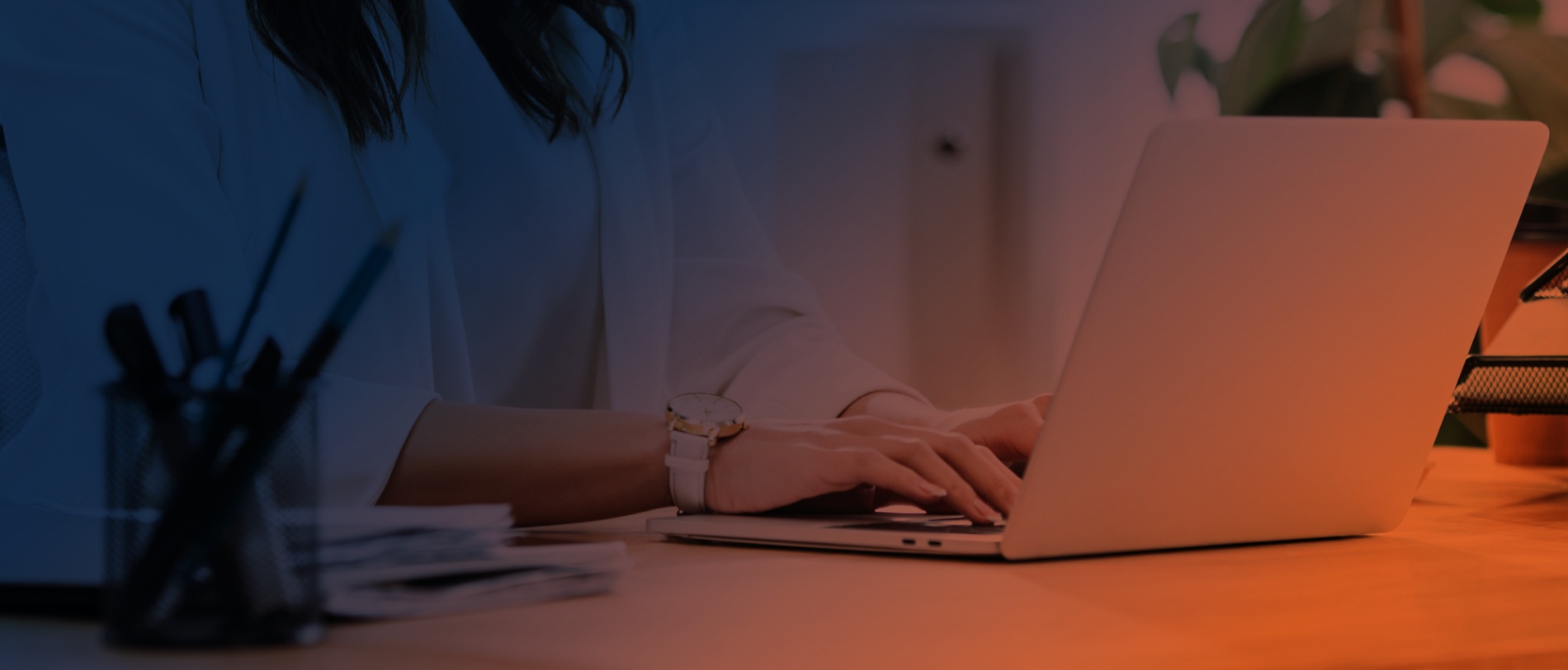 Promotional image of a person working on a laptop, with navy and orange coloring