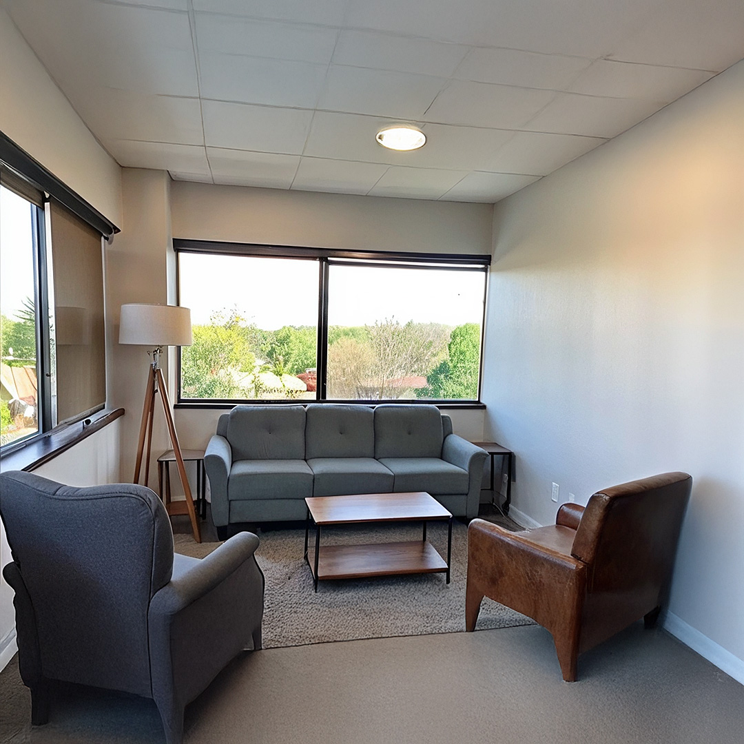 Seating area with armchairs, a sofa and large windows in an office image published by Serene Health