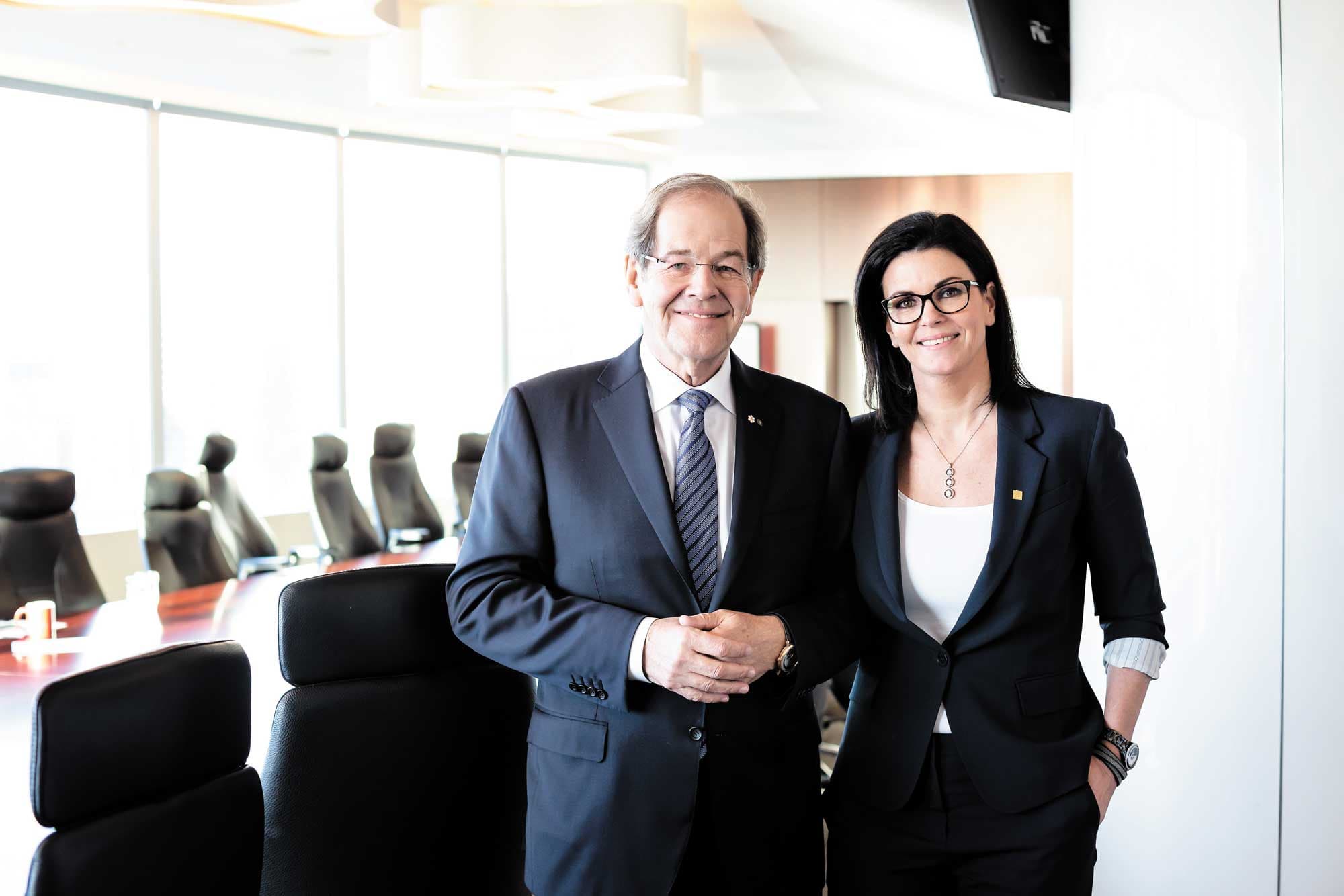 Serge Godin and Julie Godin standing together in a CGI boardroom