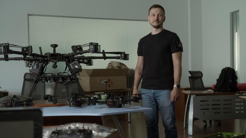 Serhii Kupriienko standing beside drones in a workshop