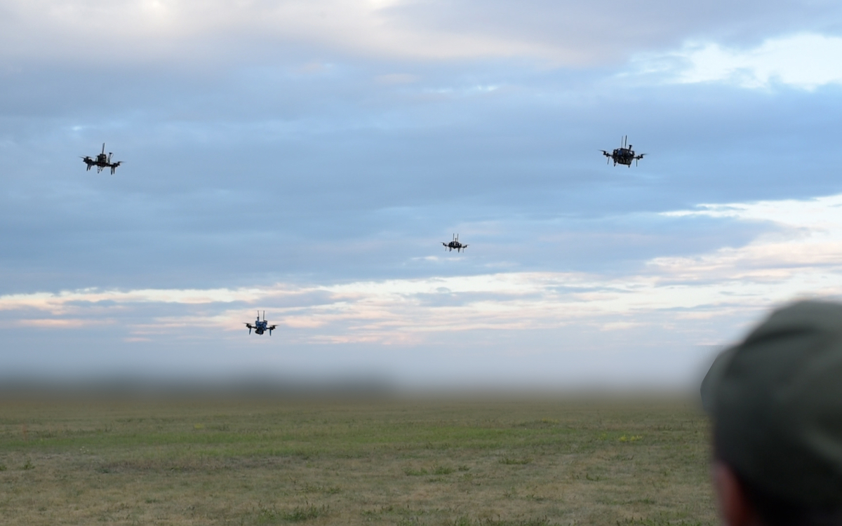 Four drones flying above a field during a Swarmer test