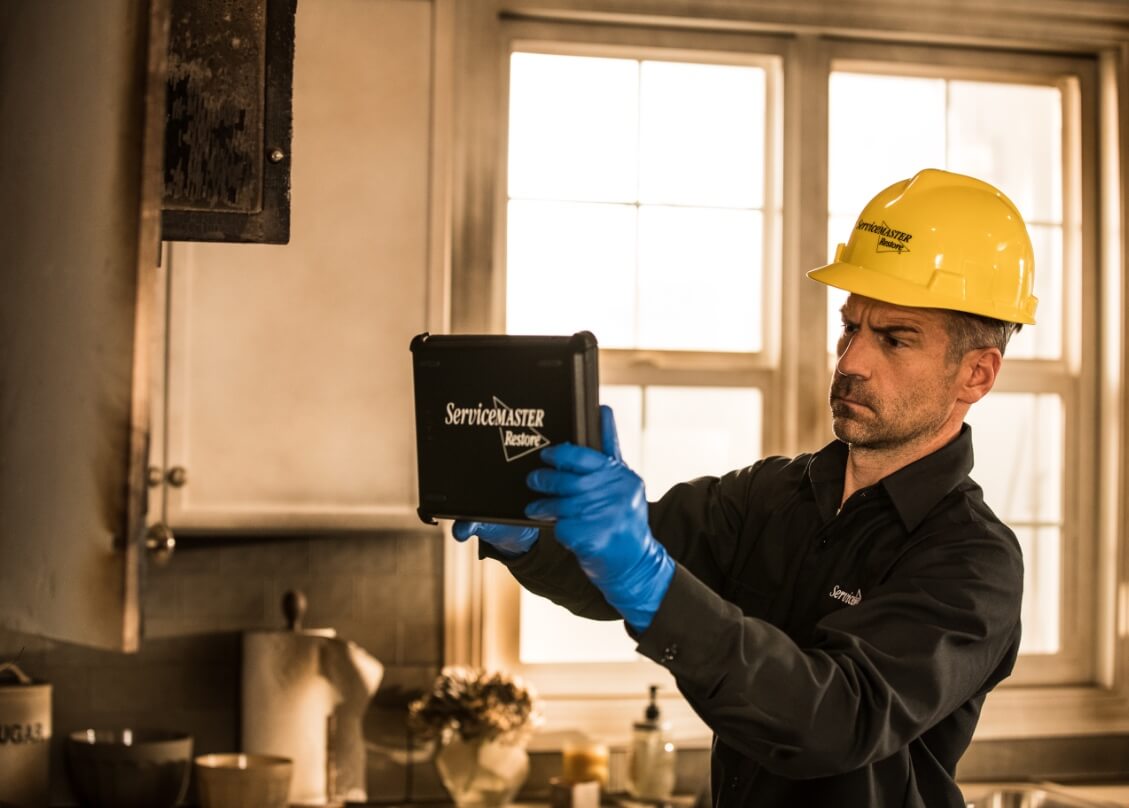 ServiceMaster Restore technician inspecting fire damage with a tablet