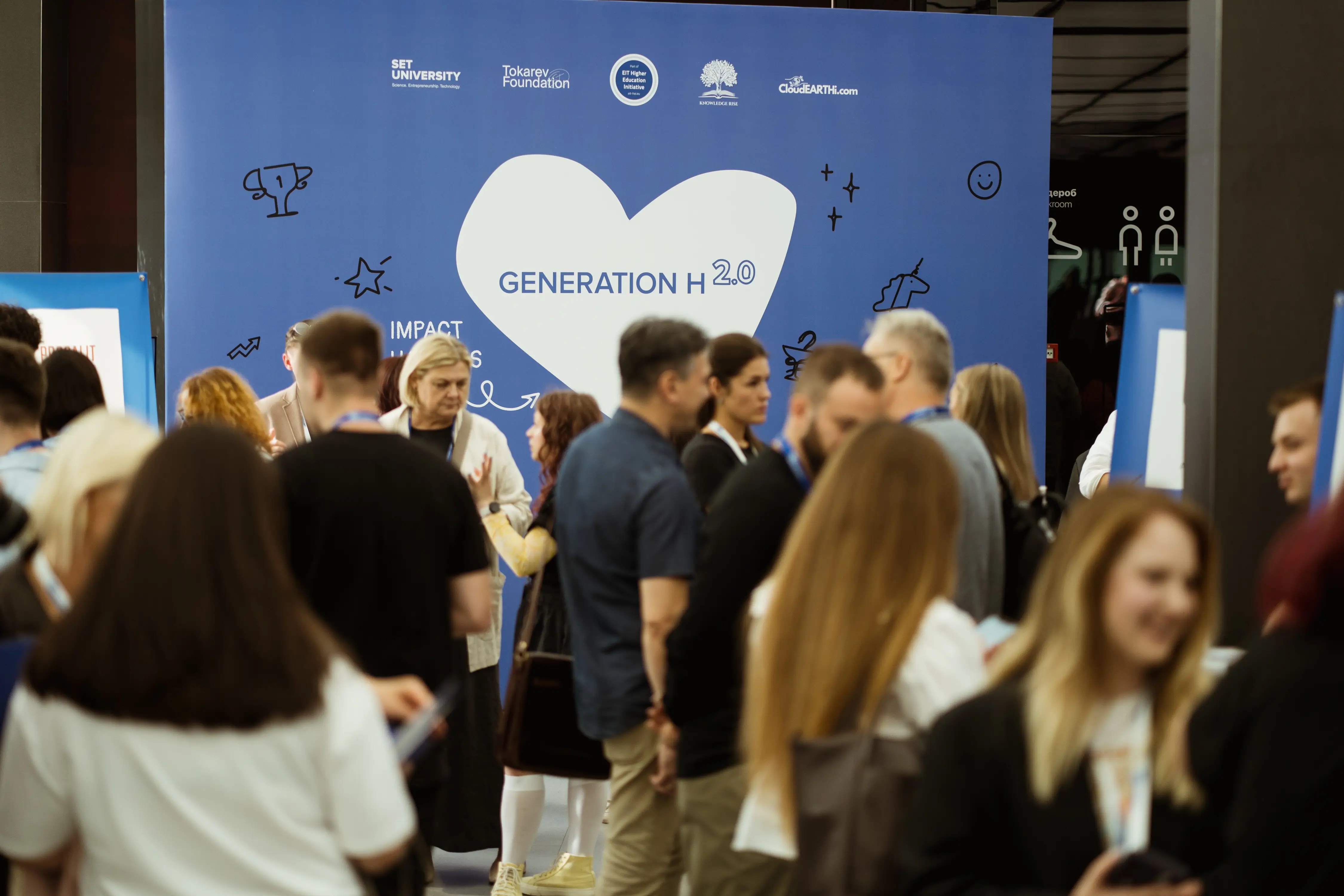 Participants talking in front of the Generation H 2.0 backdrop at its Kyiv final event