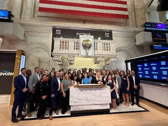 Evolent employees posing for a group photograph beneath the NYSE bell