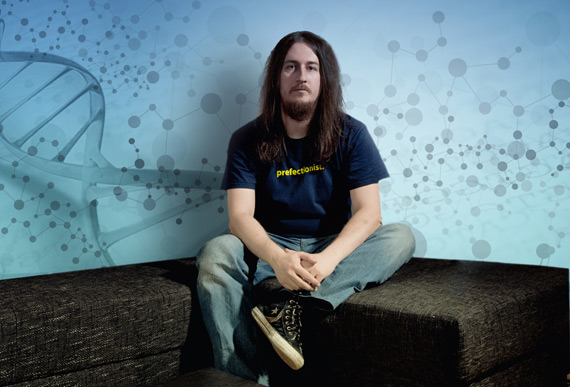 Seven Bridges co-founder Igor Bogicevic seated in front of a blue wall illustrated with molecular patterns
