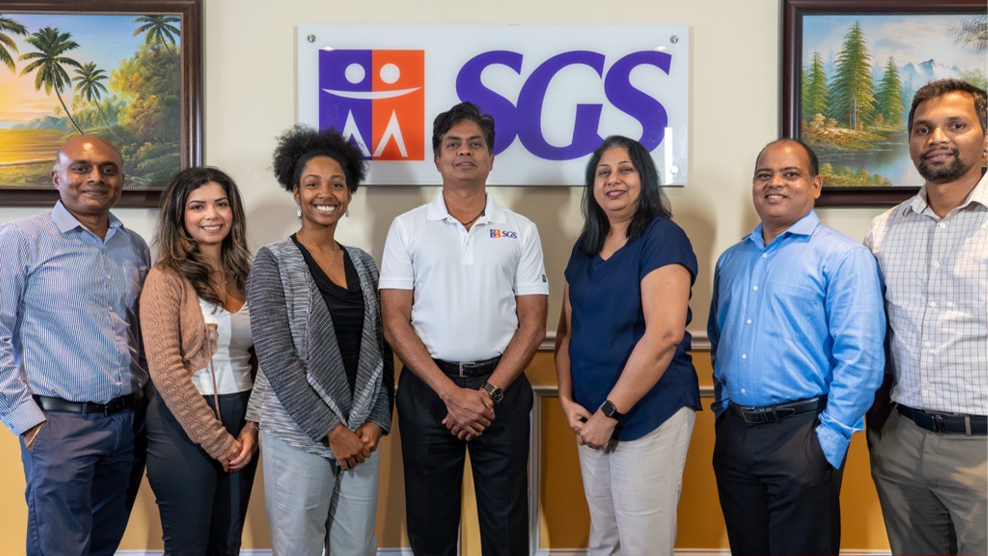 A group photographed at SGS Technologie in front of its office sign