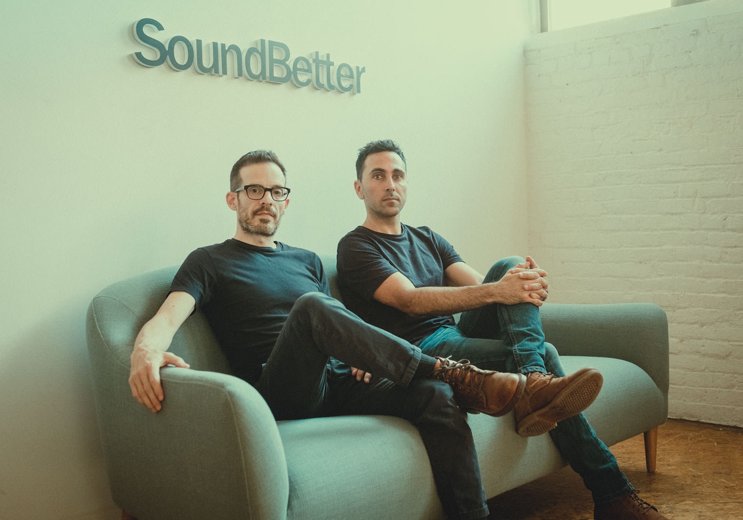 Shachar Gilad, left, and SoundBetter co-founder Itamar Yunger seated together beneath the company sign