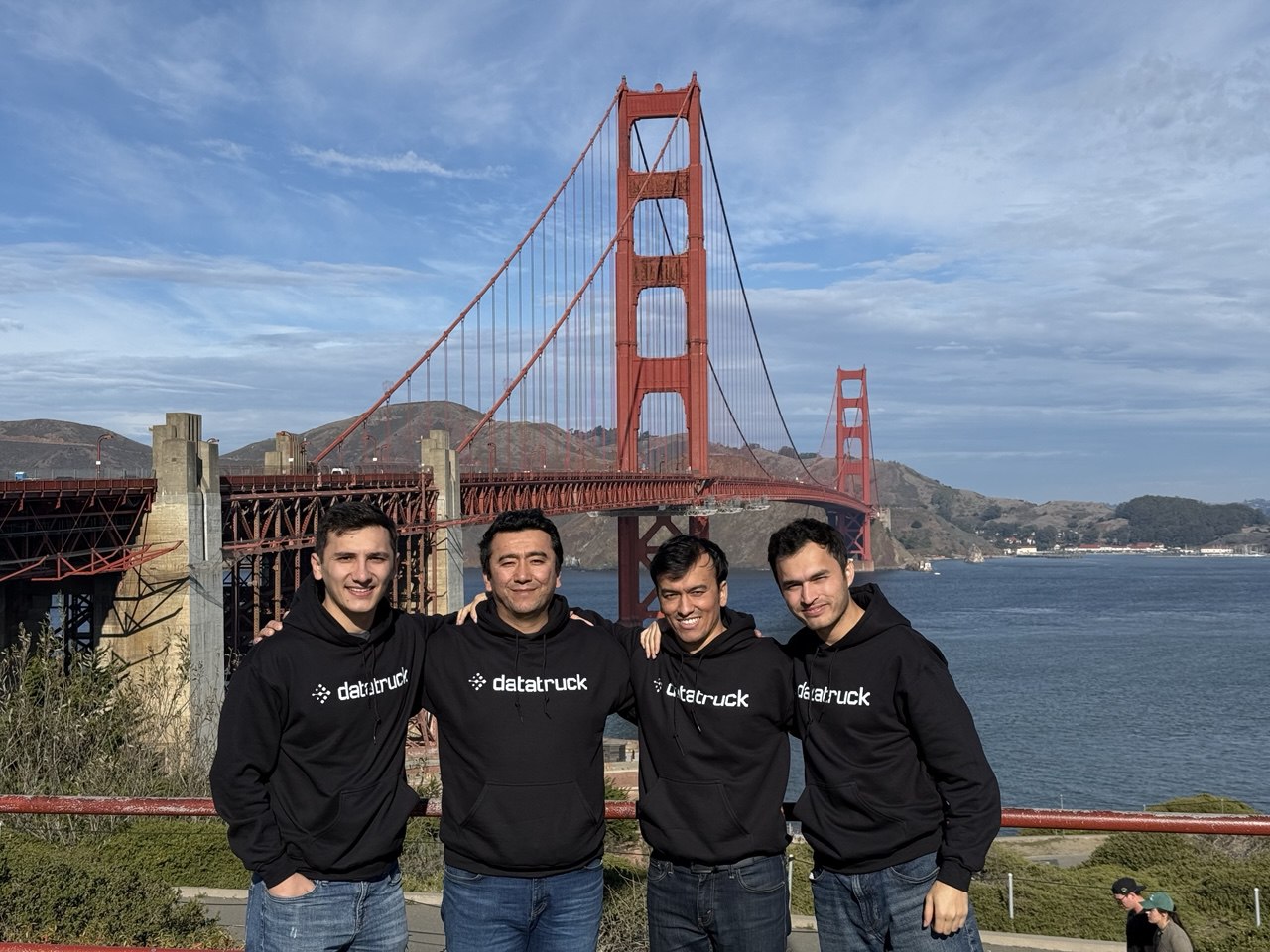 Four Datatruck team members in company hoodies standing in front of the Golden Gate Bridge