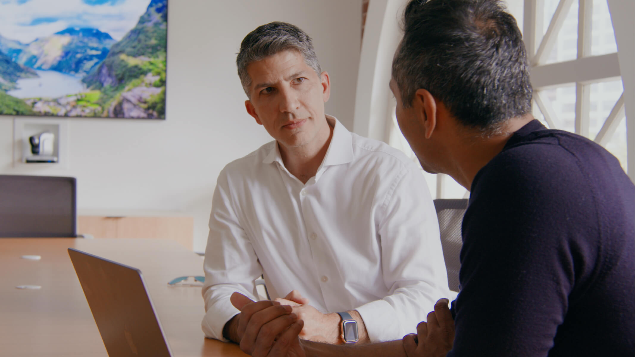 Shahram Seyedin-Noor seated at a table in conversation with another person