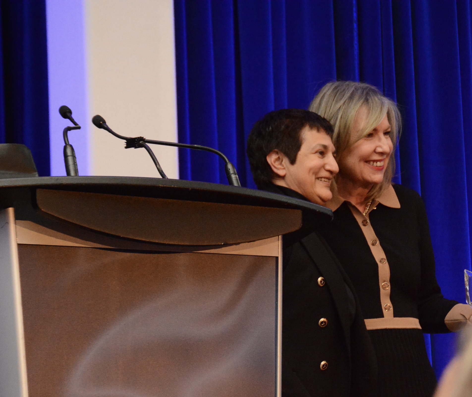 Shamira Jaffer smiling beside another attendee at the podium during the 2023 Canadian Women Entrepreneur Awards gala