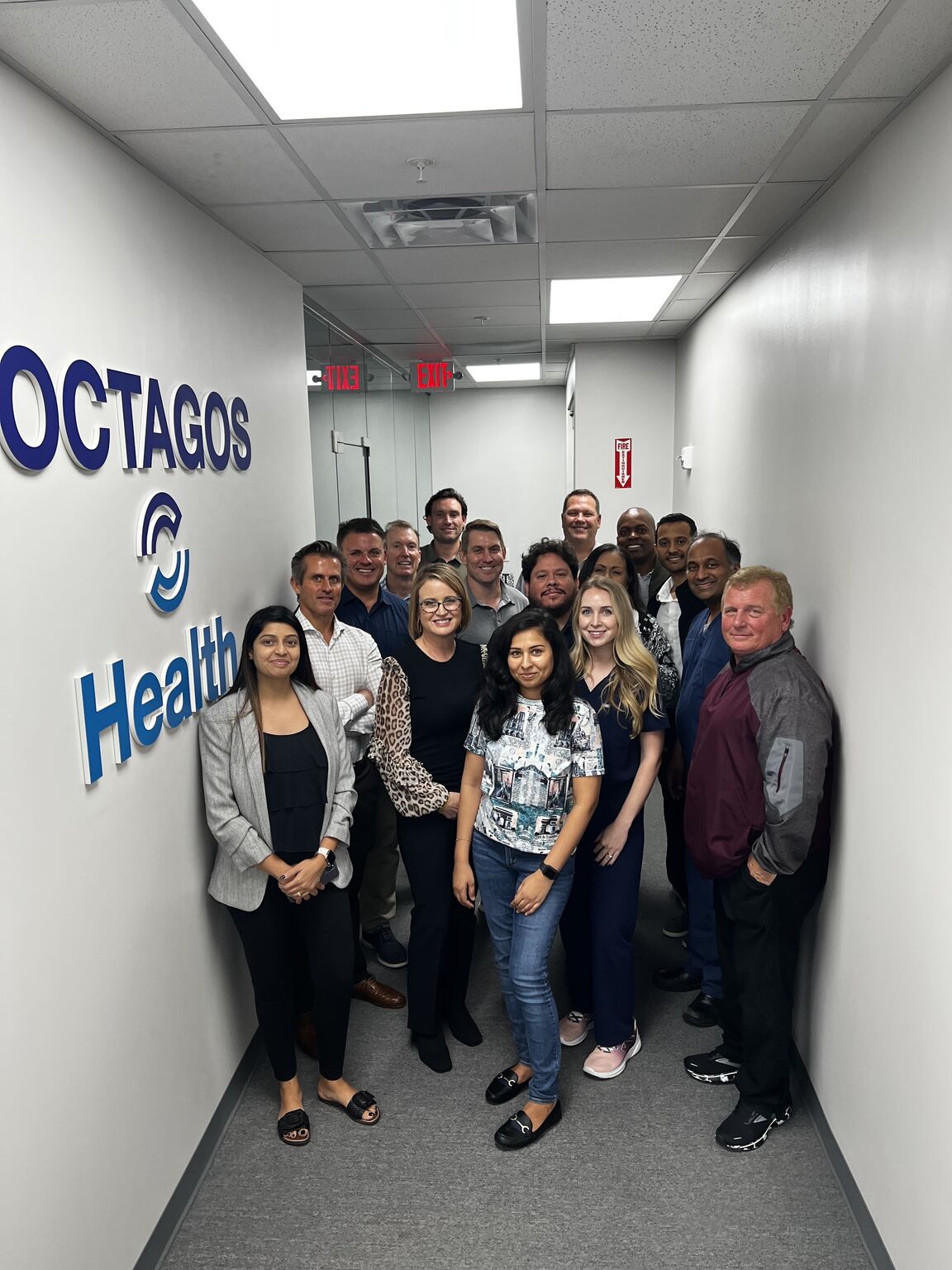 Shanti Bansal standing with members of the Octagos team in the company's office hallway
