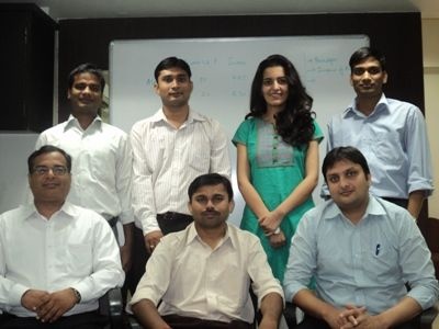 An early Valuefy team photograph, with colleagues standing and seated in front of an office whiteboard.