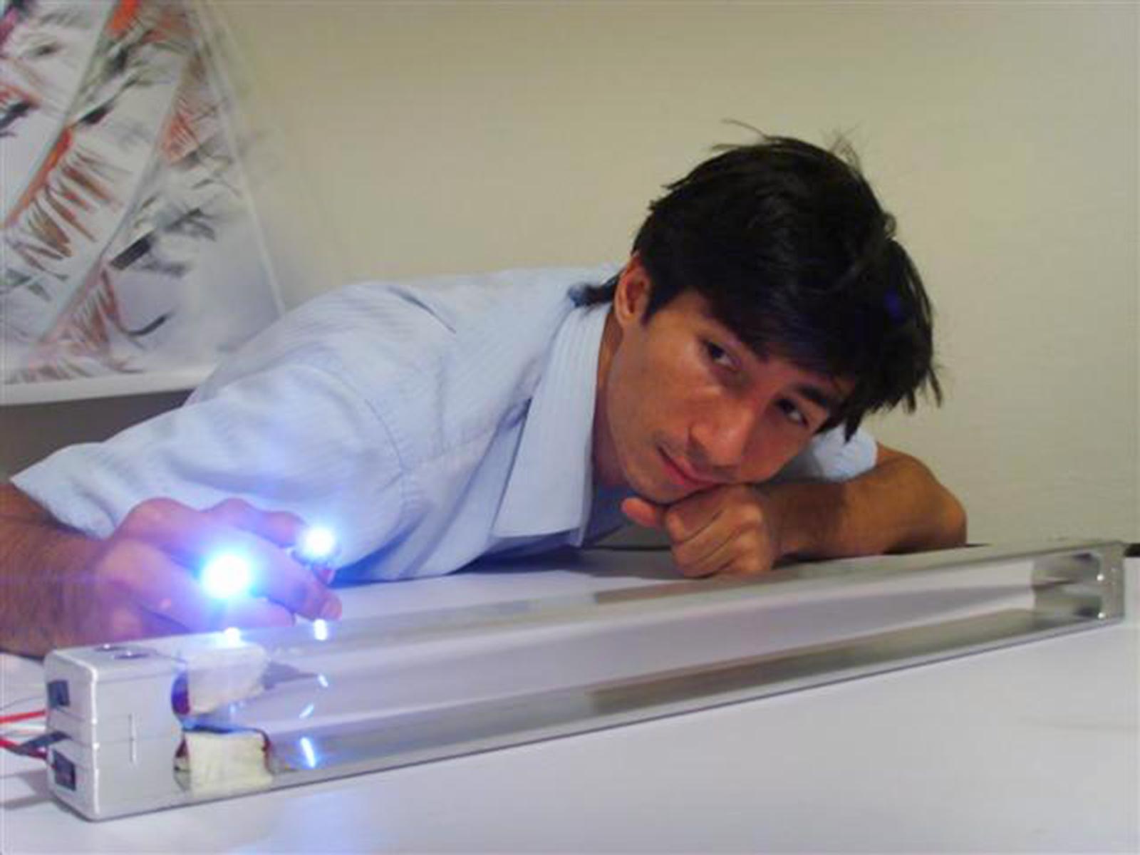 Shawn Frayne beside a Windbelt device, holding two glowing LEDs