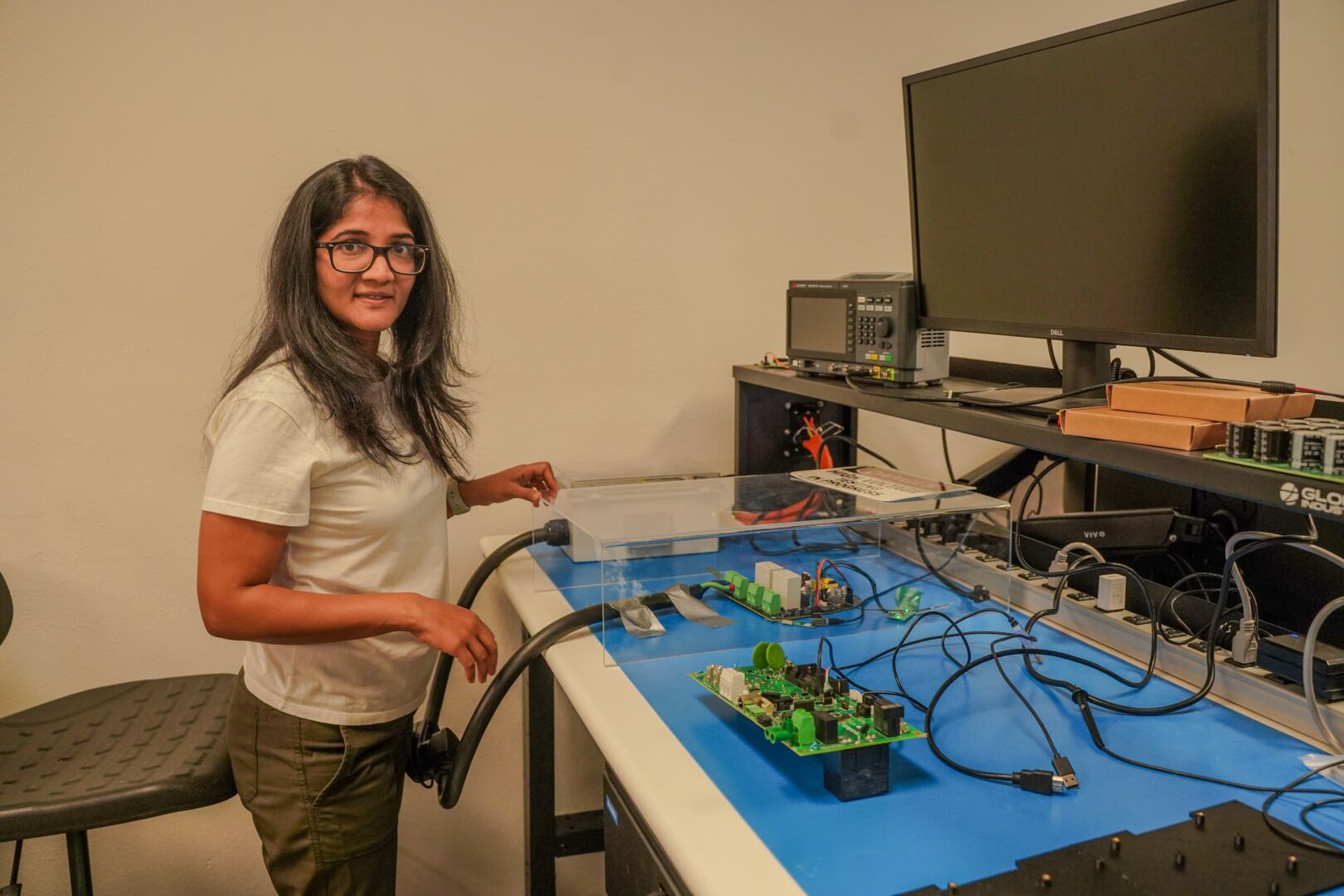An Emporia team member beside an electronics workbench with circuit boards and test equipment