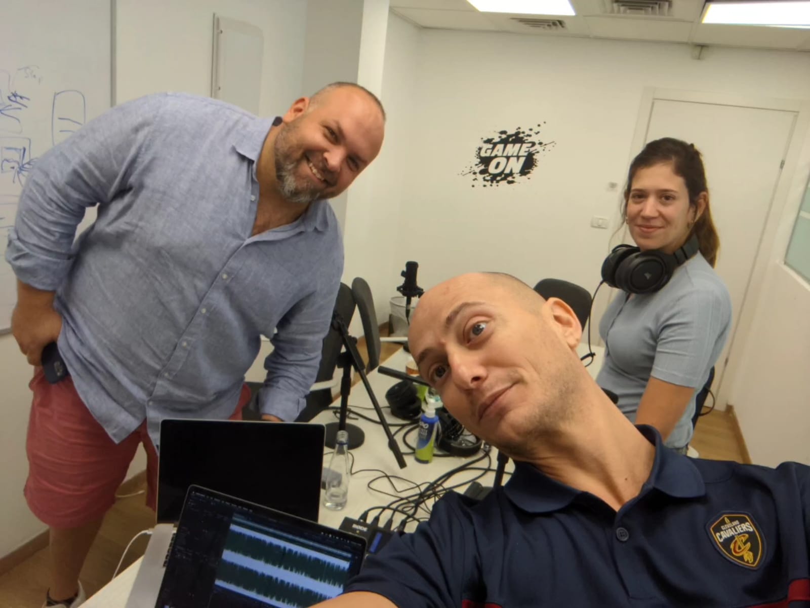 Shay Eyal, at right wearing headphones, with two fellow participants in a podcast recording room