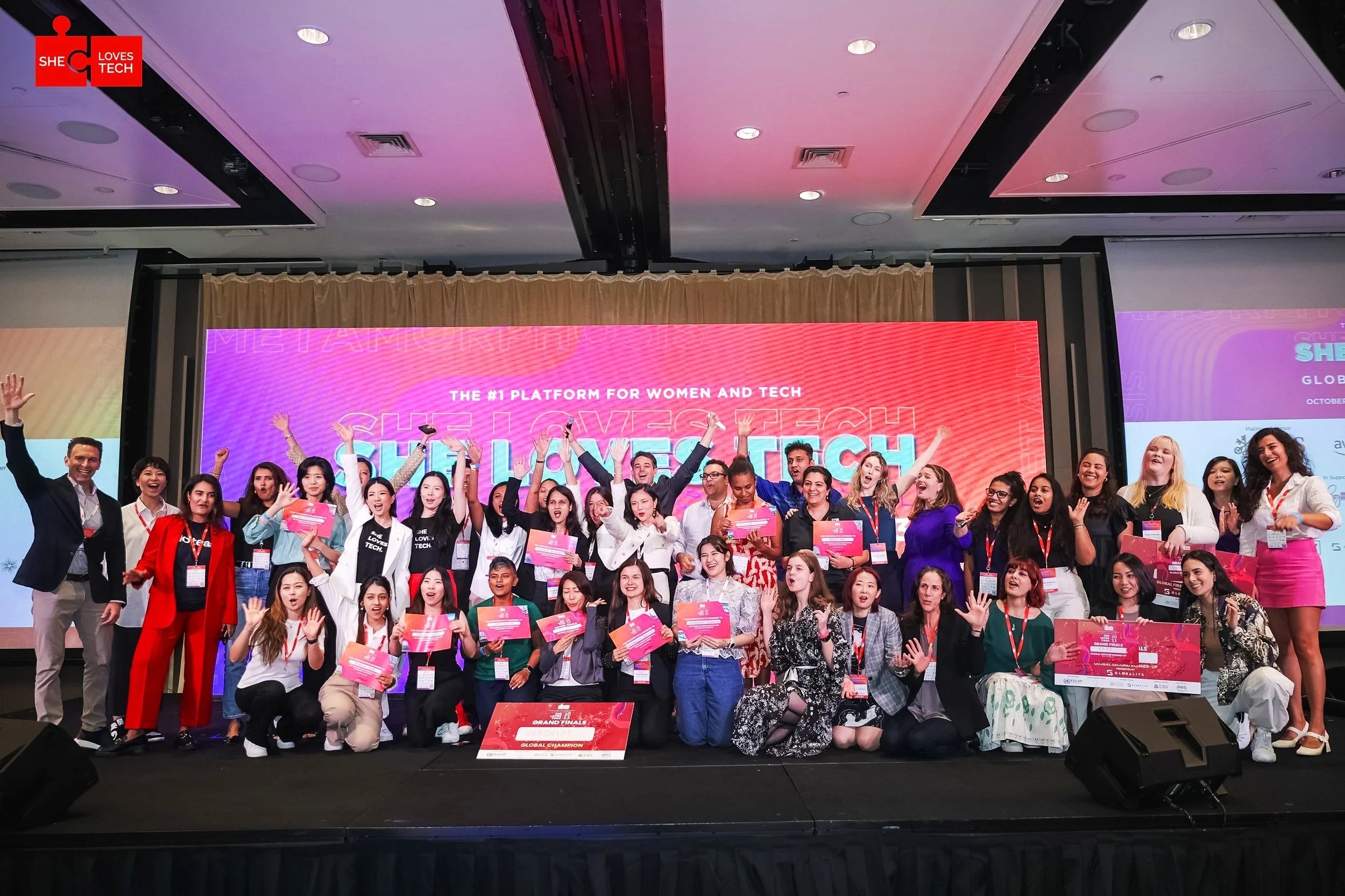Founders and participants celebrate together on a She Loves Tech event stage