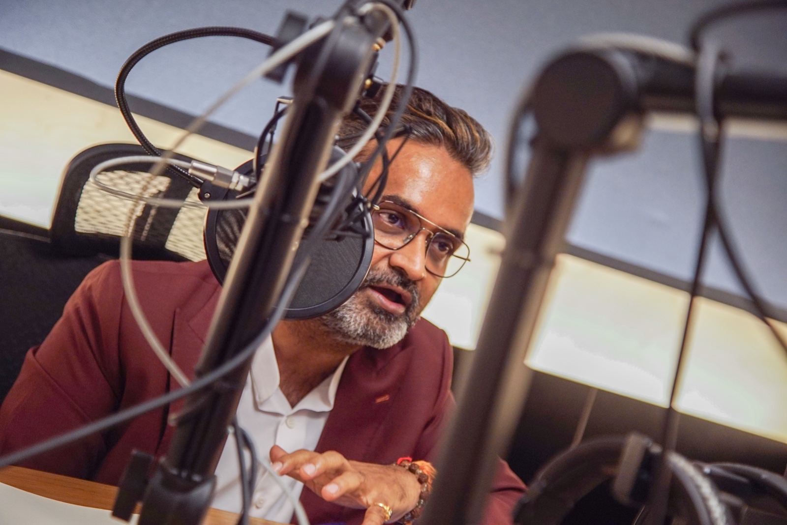 Shekar Natarajan speaking into a microphone in a podcast studio