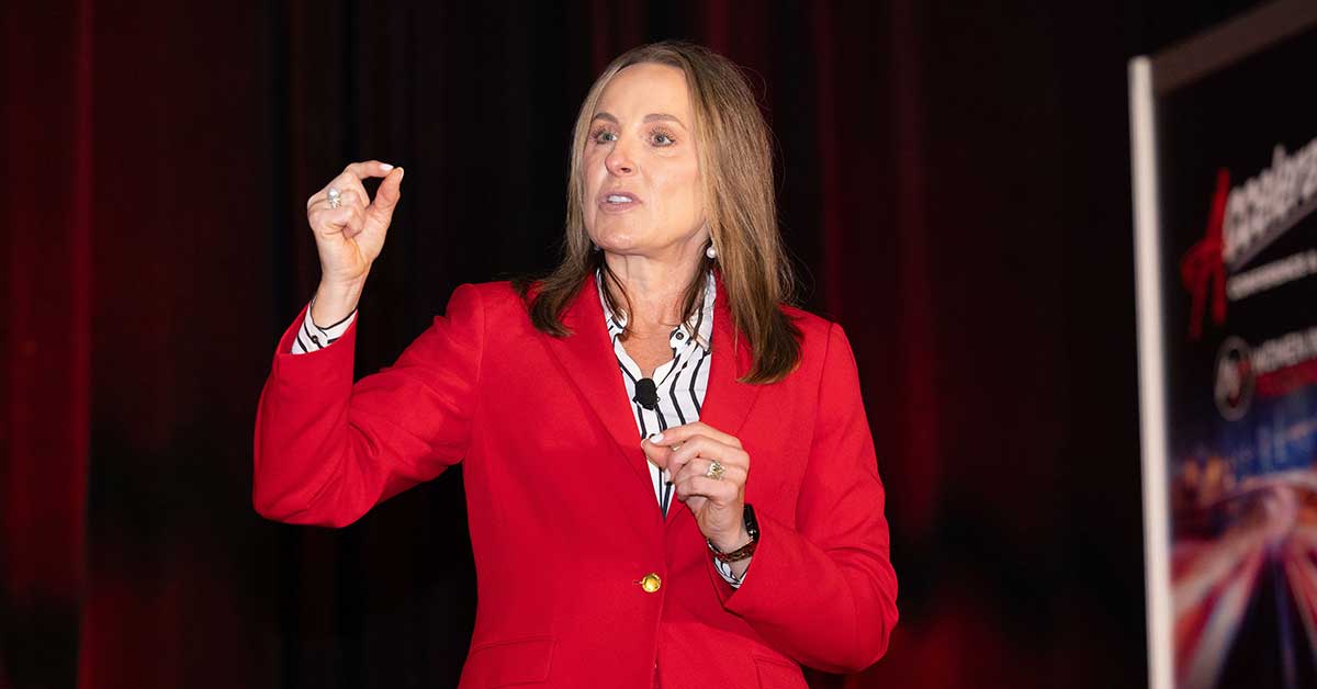 Shelley Simpson speaking in a red jacket at the 2023 Accelerate Conference and Expo