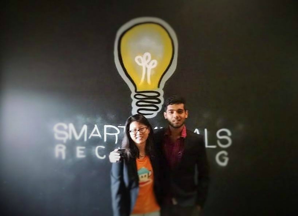 Shelly Li and Arun Karottu standing together in front of a Smart Metals Recycling wall