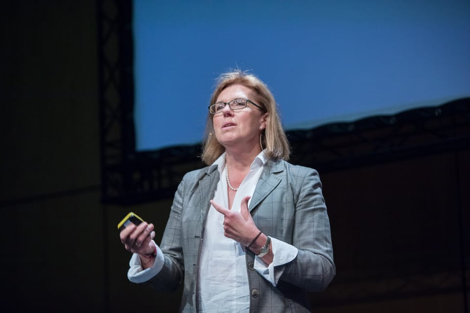 Sherry Coutu speaking on stage at Turing Fest, holding a presentation clicker