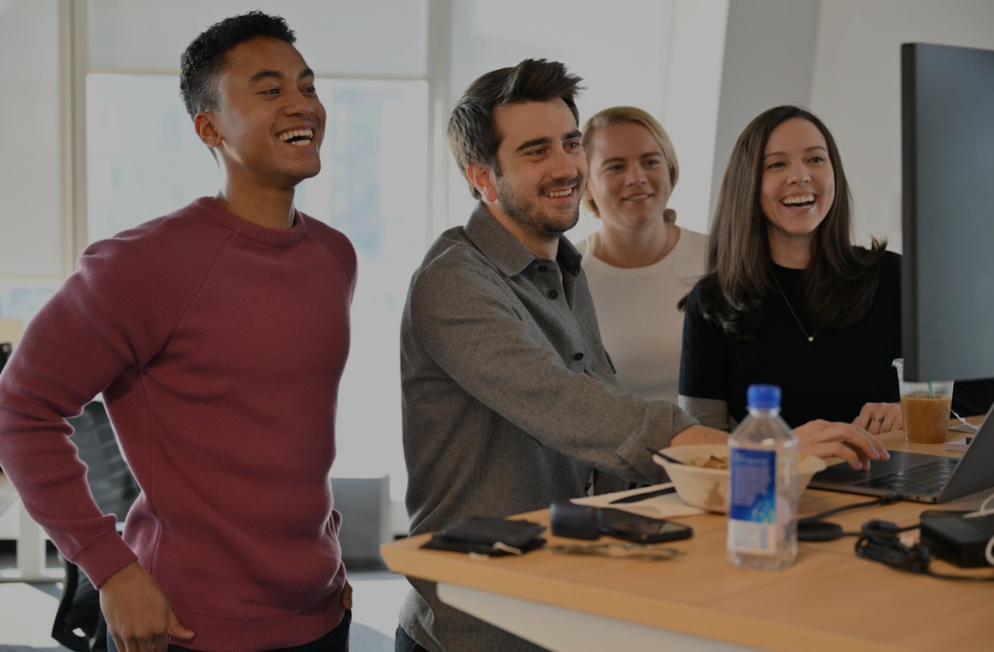 Four Shiftsmart colleagues gathered around an office computer