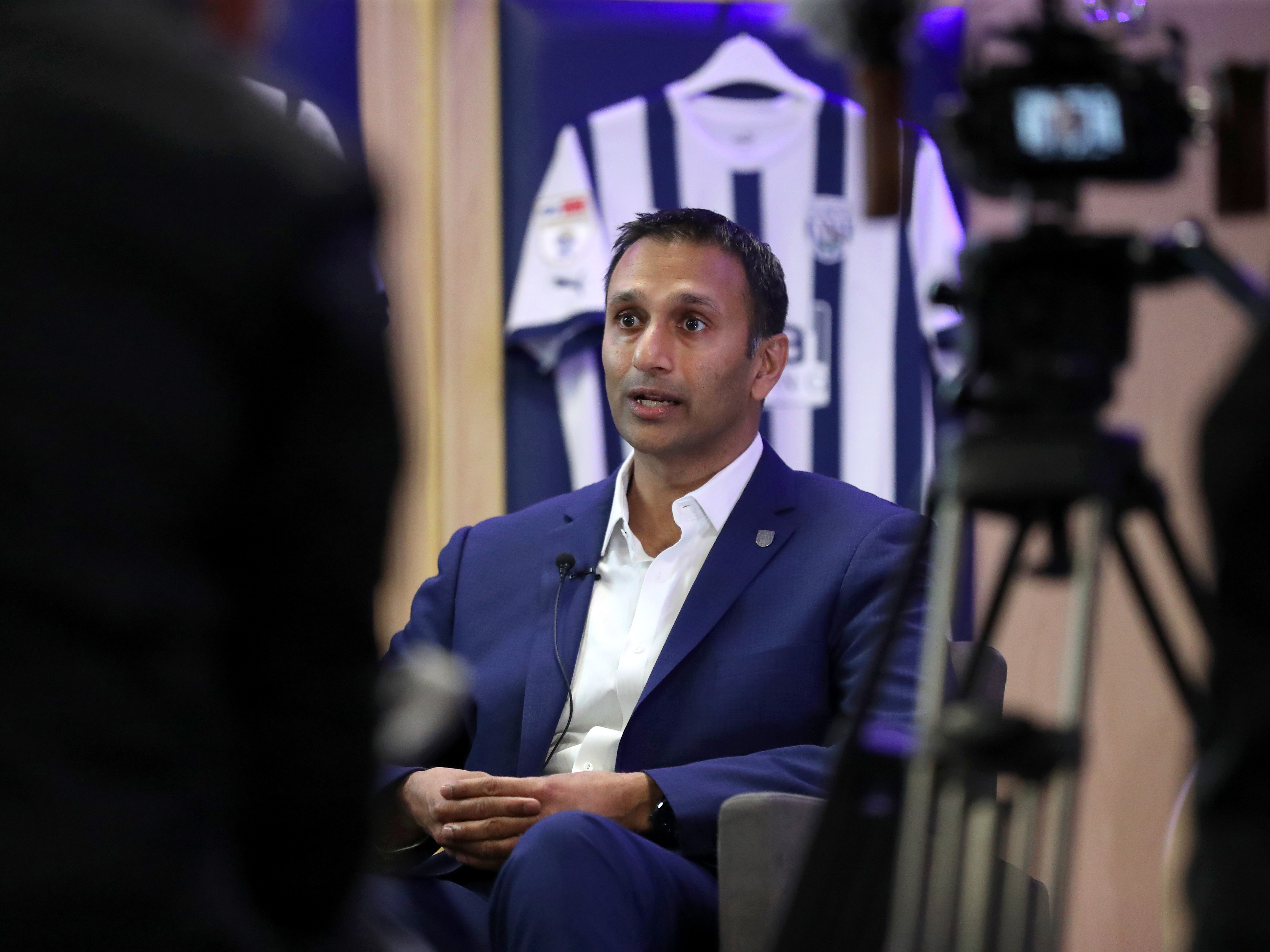 Shilen Patel sits for his first WBA TV interview in the home dressing room at The Hawthorns, surrounded by cameras and Albion shirts.