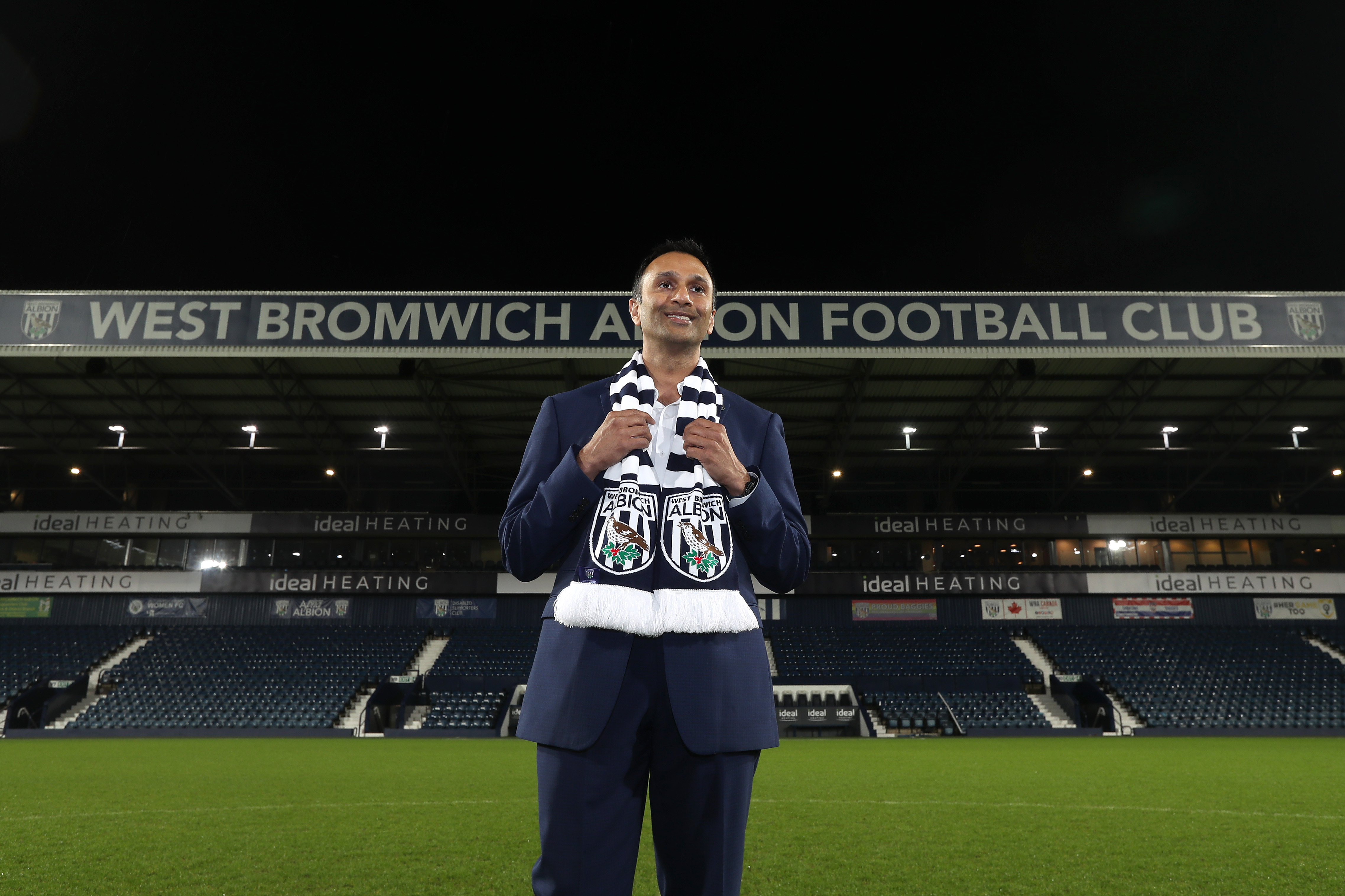 Shilen Patel stands on the pitch at The Hawthorns wearing a West Bromwich Albion scarf.
