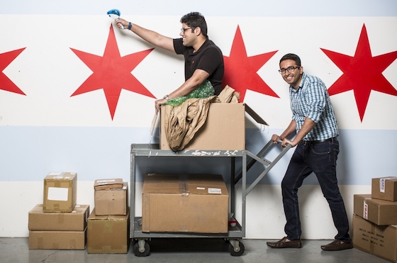 ShipBob founders posing with a handcart and cardboard boxes against Chicago stars