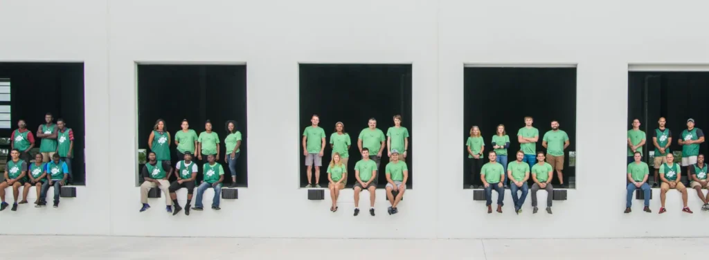 ShipMonk staff in green shirts sitting in openings along a building facade