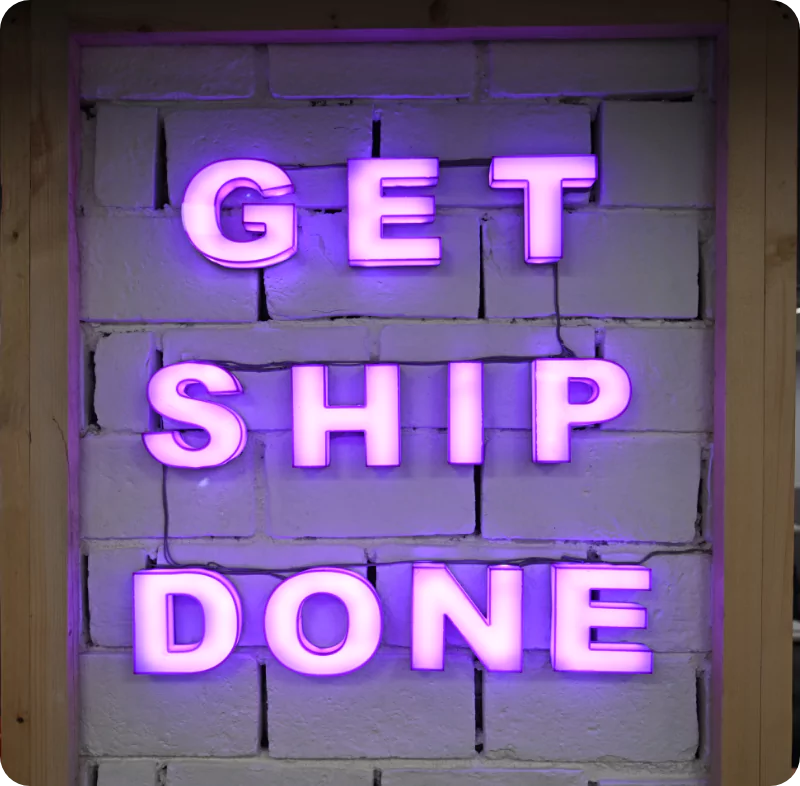 Purple illuminated letters reading Get ship done on Shiprocket’s office wall