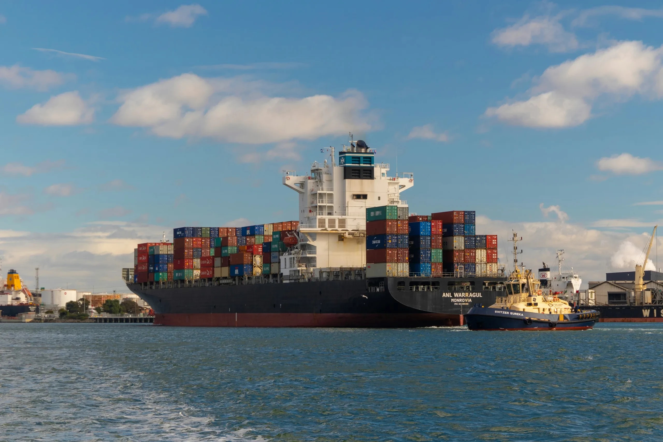 Container ship ANL Warragul alongside a tug in port