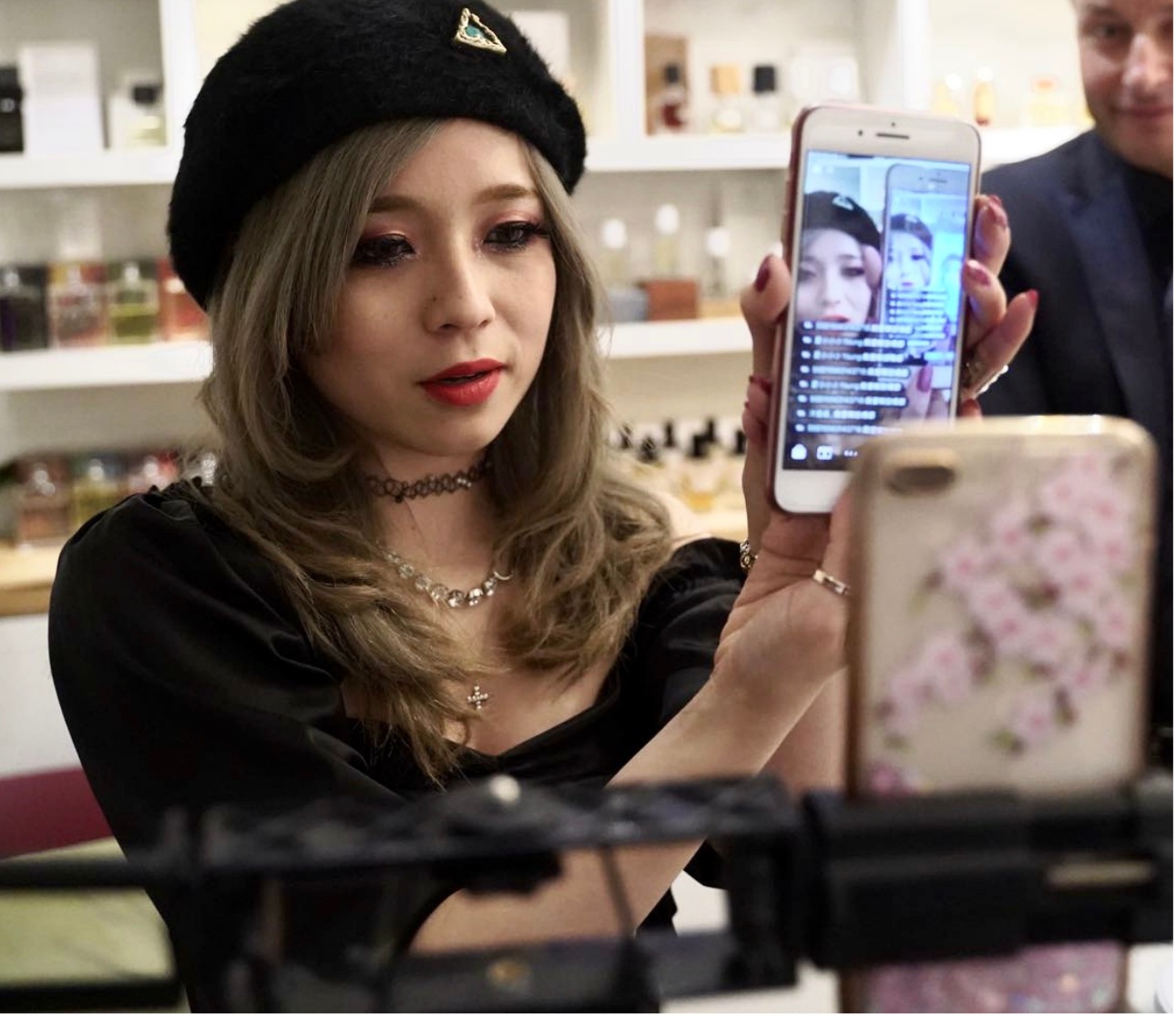 A ShopShops host holding a phone showing a live broadcast inside a shop