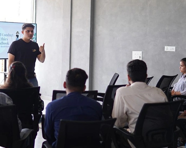 Shrey Sharma speaking to seated colleagues in a meeting room