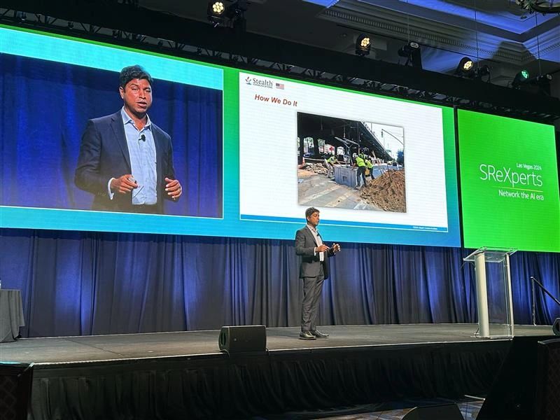 Shrihari Pandit speaking at SReXperts in Las Vegas, with a street excavation pictured on the screen