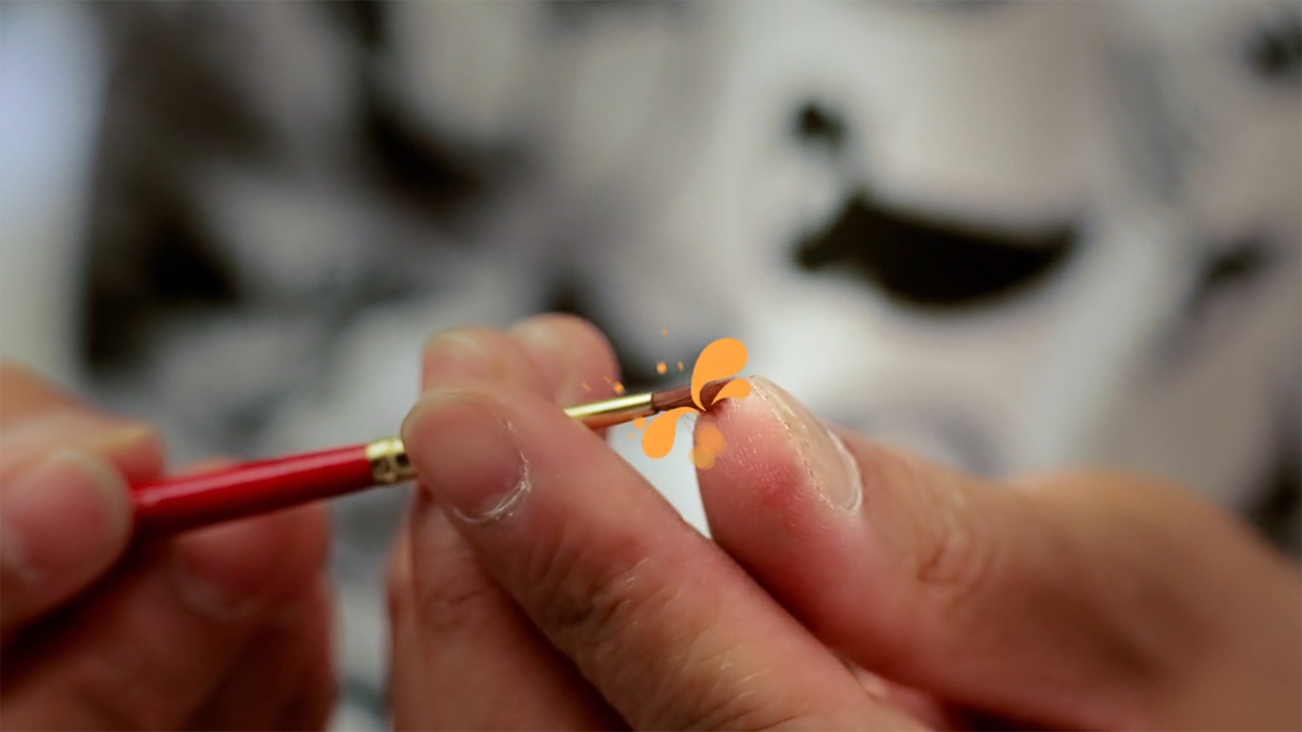 A close-up of an artist painting a small orange form at Sia/Addison