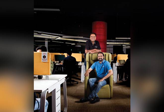 Siddharth Sethi standing behind seated co-founder Avinash Sethi in an InfoBeans office