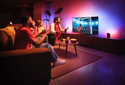 Friends watching a match in a living room lit with colored Philips Hue lighting synced to the screen