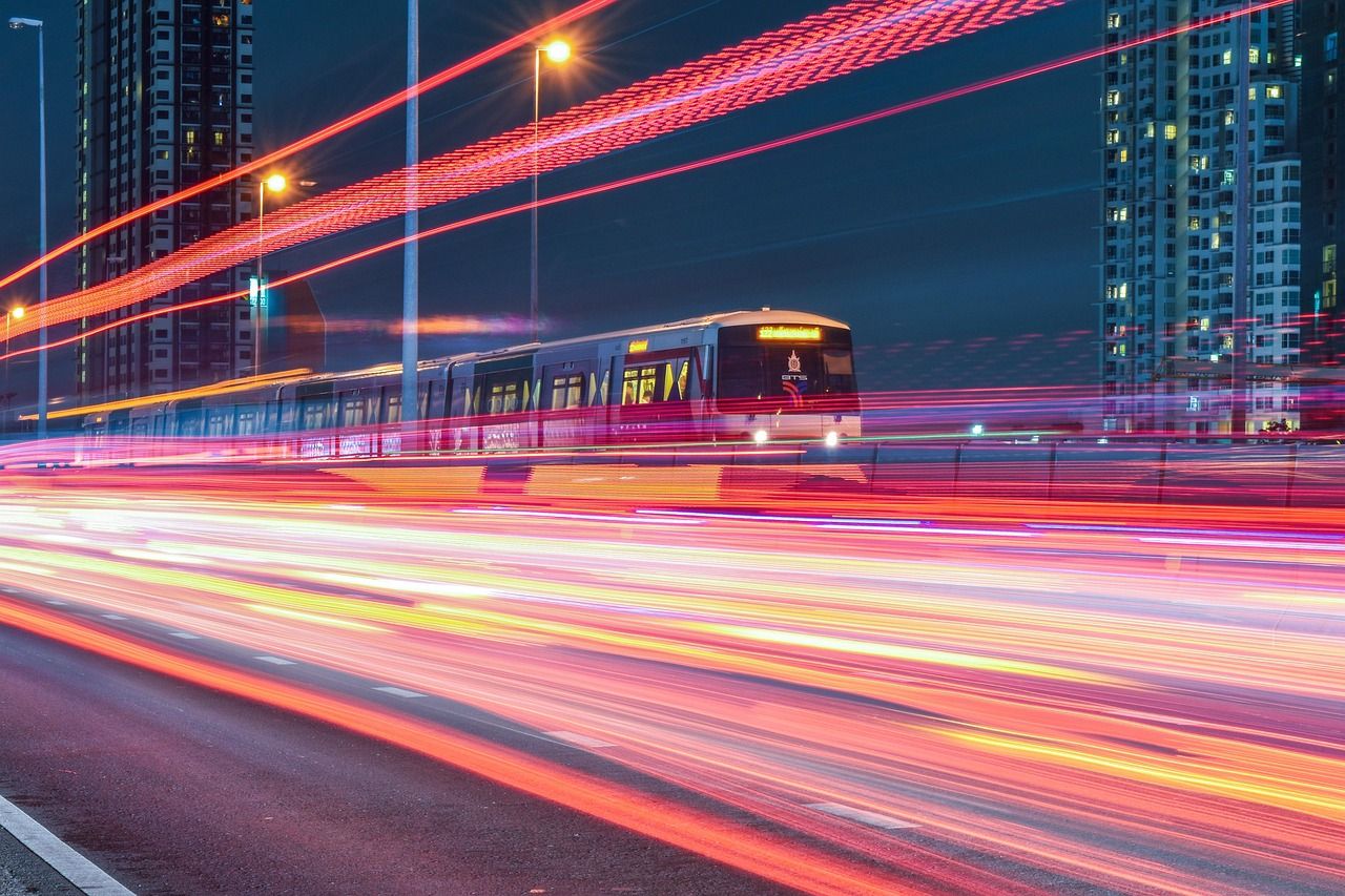 An urban train at night surrounded by long-exposure light trails