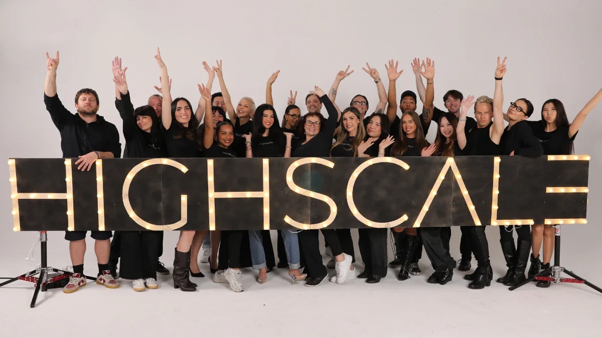 HighScale team members standing together behind illuminated HIGHSCALE letters