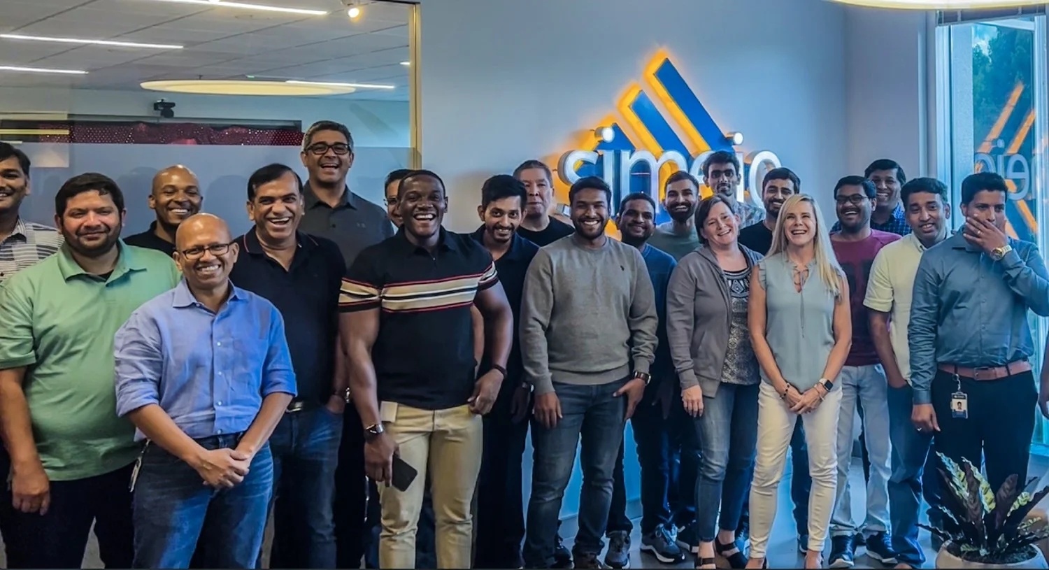 Simeio colleagues gathered for a team photograph in an office