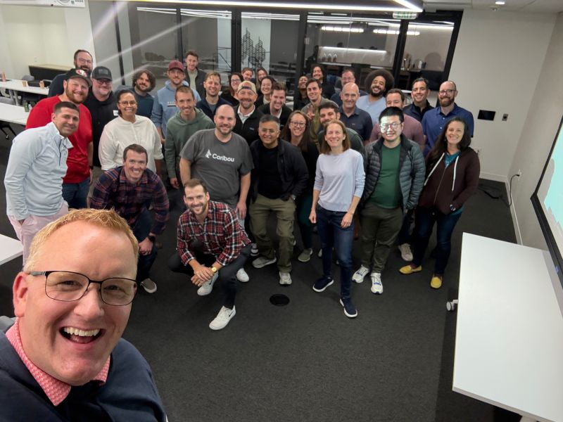 Simon Goodall taking a wide-angle group photo with Caribou colleagues in a meeting room
