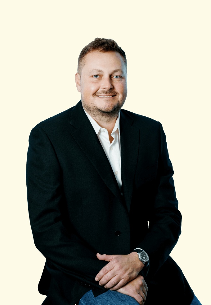 Simon Lobanov seated in a dark jacket, in B2B’s alternate team photograph