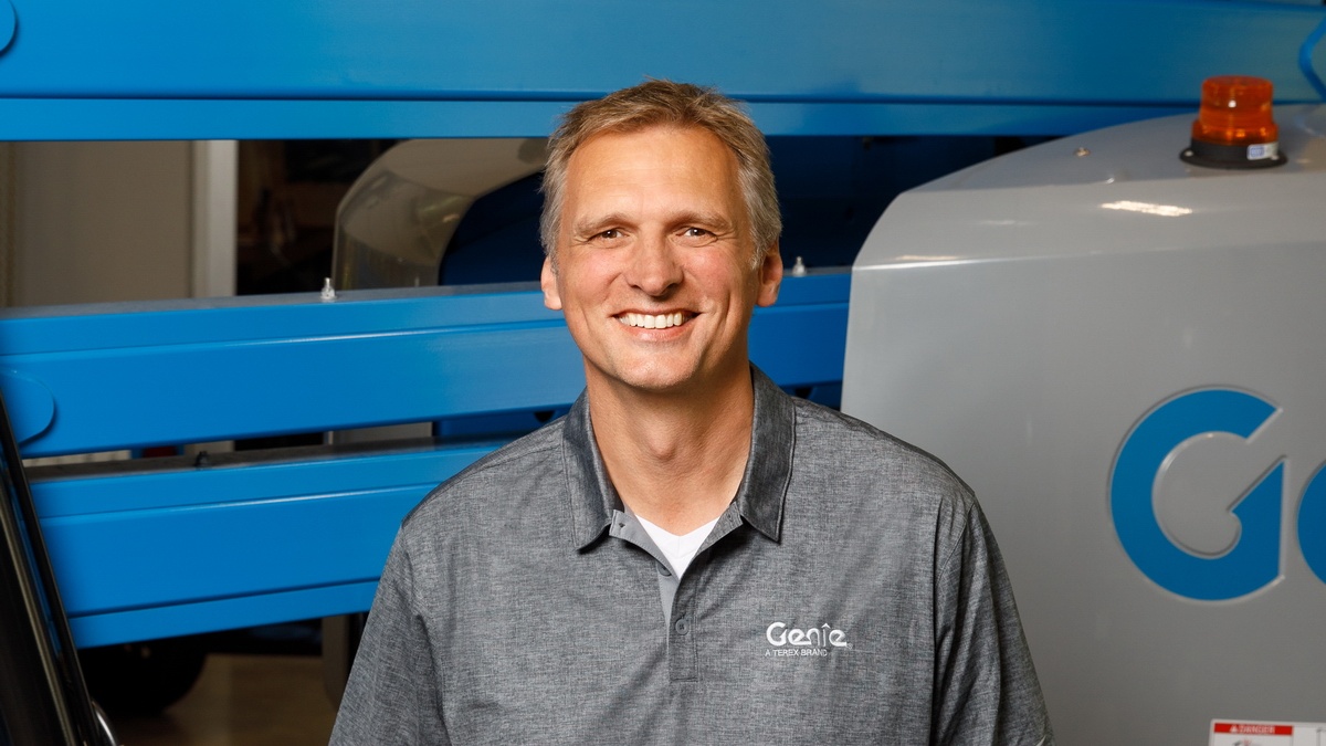Simon Meester in a Genie polo shirt standing in front of blue Genie equipment