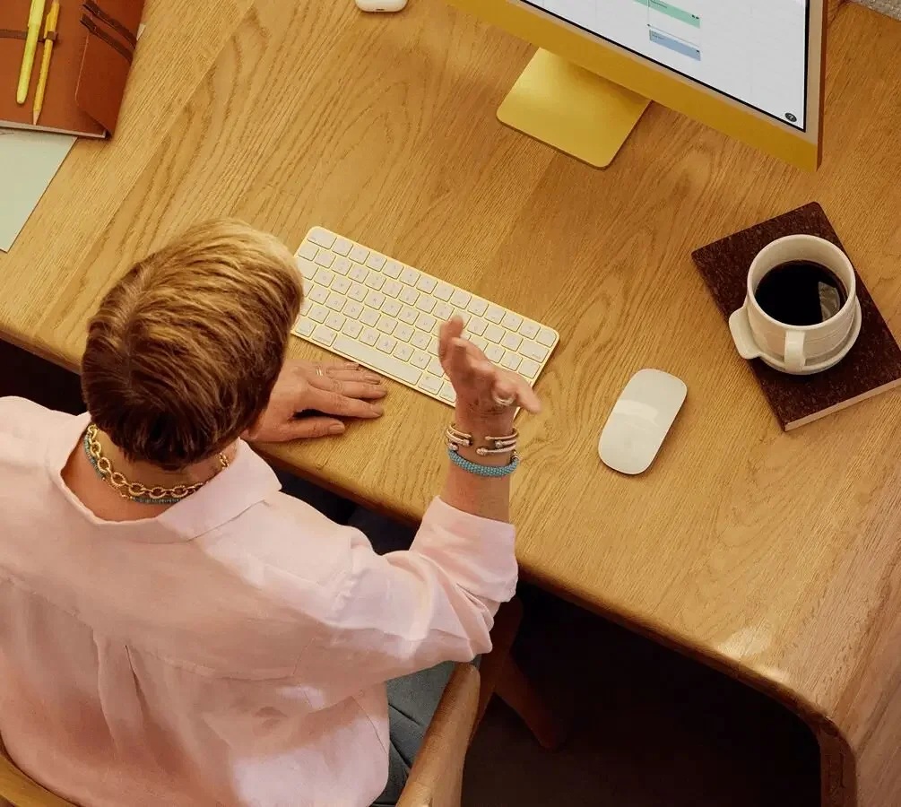 Overhead view of a person gesturing during a telehealth call at a wooden desk