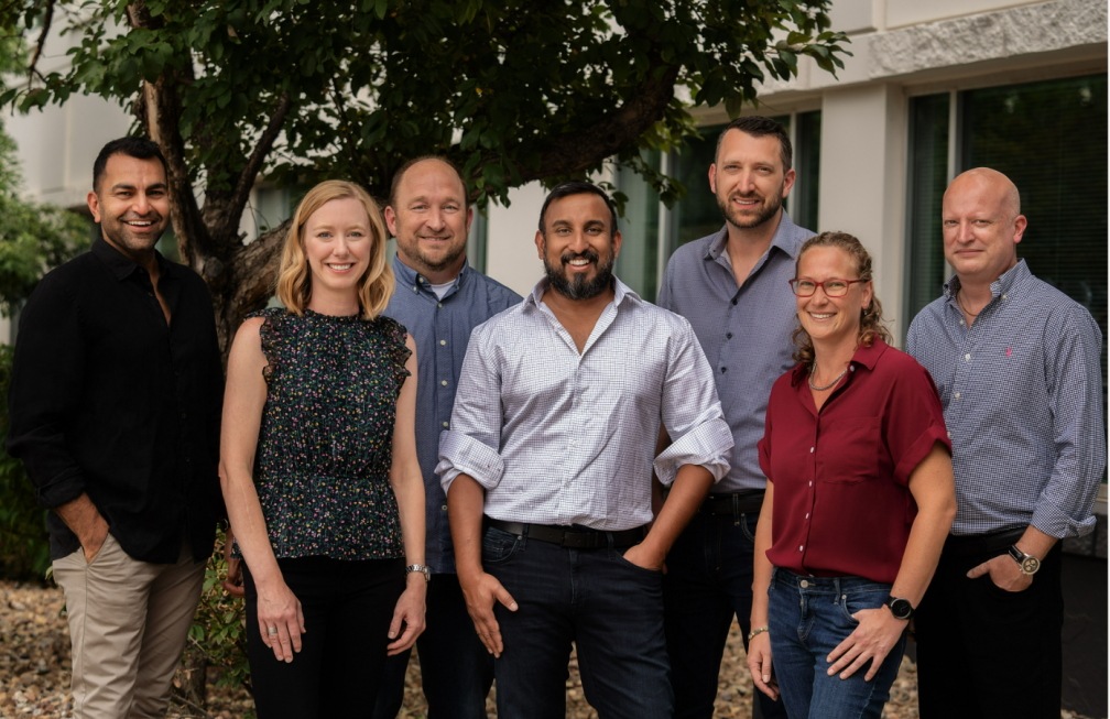 Seven members of the historical Simpro team standing outside a building
