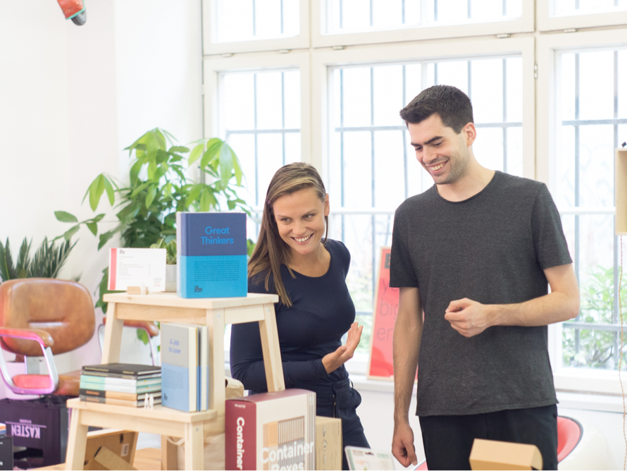 Sissel Hansen and a colleague smiling beside a display of books