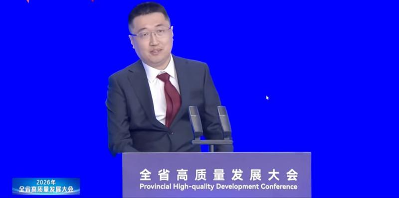 Sky Xu in a dark suit and burgundy tie speaking at the 2026 Guangdong Provincial High-Quality Development Conference