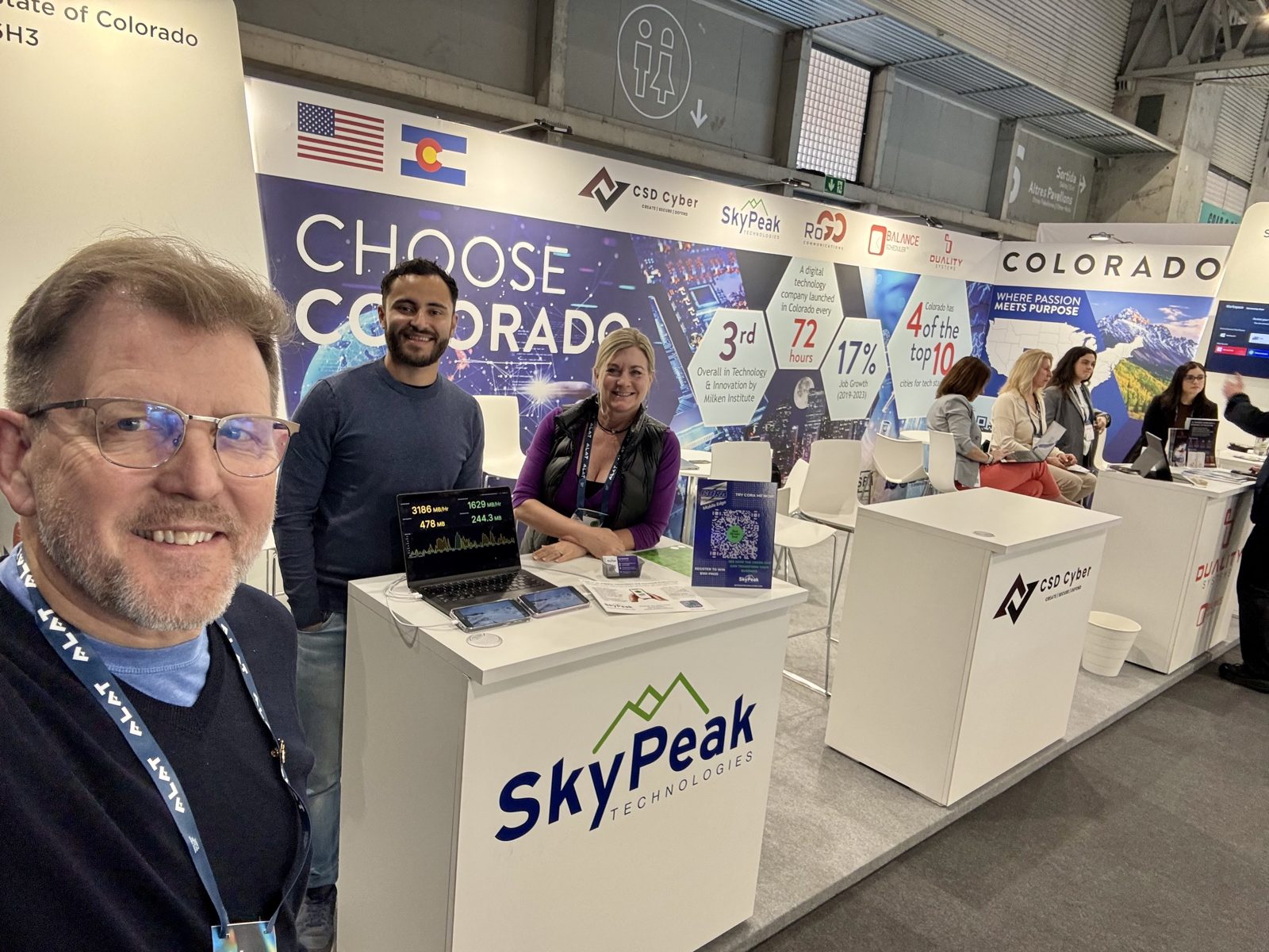 Sky Peak Technologies team at their Mobile World Congress booth in Barcelona under a Choose Colorado banner