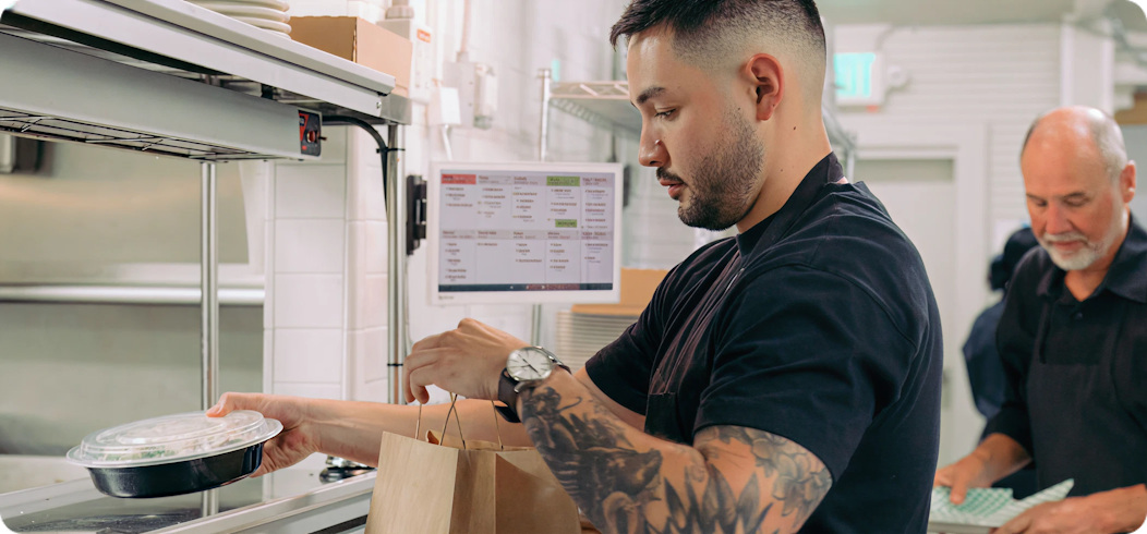 Restaurant workers packing a takeaway order in a commercial kitchen